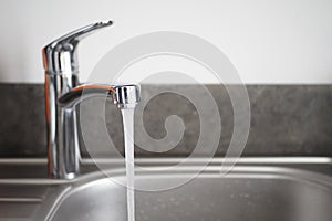 Water dripping from faucet tap at kitchen. Closeup