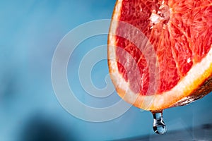 Water drips from half a grapefruit. Splashes and drops fly from a piece of grapefruit symbolizing the brightness and freshness of