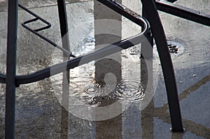 Water drips under the furniture on a patio after a rain squall as the sun breaks through