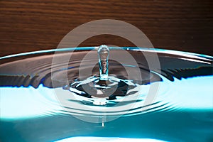 Water drop on blue background. Blue water surface with splash. Clear Waterdrop with circular waves. Splashes closeup. Water splash