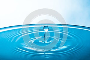 Water drop on blue background. Blue water surface with splash. Clear Waterdrop with circular waves. Splashes closeup. Water splash