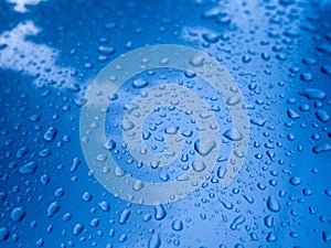 Water drop on blue metal reflect with blue sky and white cloud for background in rainy season