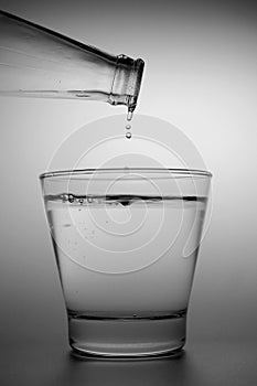 Water drop from the bottle to the small glass