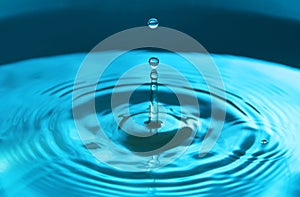 Water drop falling into water making a perfect concentric circles. Abstract blue background
