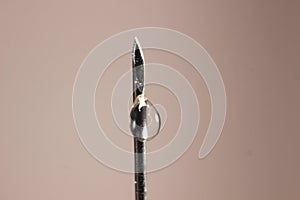 Water drop falling from the syringe needle against grey background