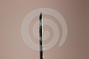 Water drop falling from the syringe needle against grey background
