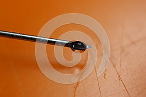 Water drop falling from the syringe needle against orange background