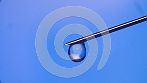 Water drop falling from the syringe needle