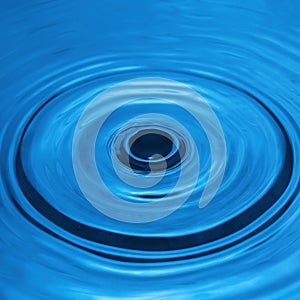 Water drop falling into water making a perfect droplet splash in blue