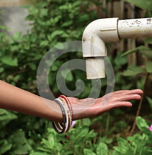 Water drop pours from the old crane into the hands of a woman. The concept of water scarcity