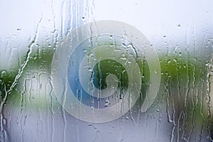 Water drop, rain drop on glass and dripping down with green bac