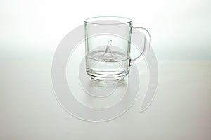 Water drop in transparent glass on gray background. purified drink water on table
