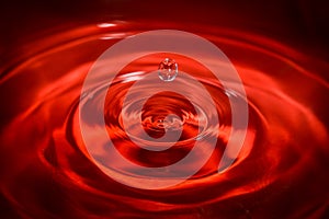 Water drop an waves with red background and reflection