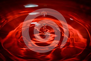 Water drop an waves with red background and reflection