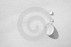 Water drop on white paper textured background with copy space and selective focus, close-up. Concept moisturizing macro