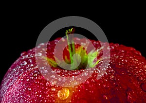 Water droplet on glossy surface of red apple on black background