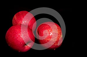 Water droplet on glossy surface of red apple on black background