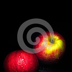 Water droplet on glossy surface of red apple on black background