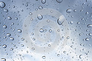 The water droplet from raindrop on clear mirror under cloudy blue sky, close up photo