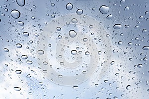 The water droplet from raindrops on clear mirror under cloudy blue sky, close up photo