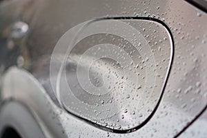 The water droplet from raindrops on silver color car`s body, the dew cover on the petrol tank`s cover, close up photo