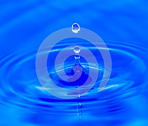 Water droplets falling in blue water