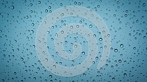 Water droplets on glass surface with soft blue background
