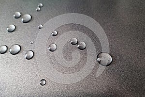 Water droplets on a gray metal surface.