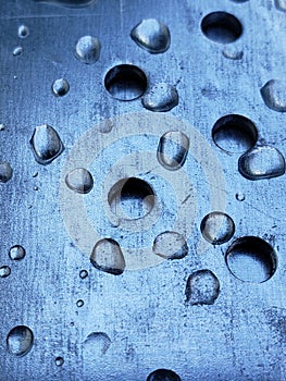 Water droplets on a metal plate with holes, close-up. Macro photo