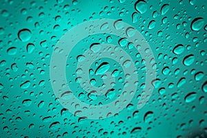 Water droplets scattered on cyan blue glass for background.