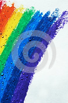 There are drops of water dripping over a rainbow with crayons.