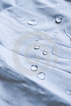 Water droplets on white fabric drapery with folds shining in light