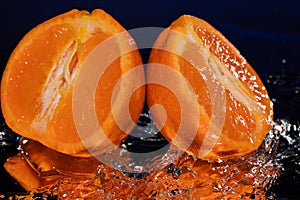 Water drops around mandarin on mirror blue background