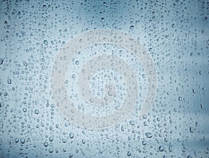 Water drops on glass window over blue sky