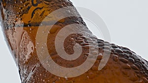 Water drops beer bottle flowing in super slow motion closeup. Cold alcohol drink