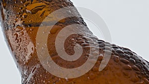 Water drops beer bottle flowing in super slow motion closeup. Cold alcohol drink