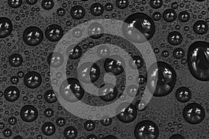 Water drops on black background texture. Dark backdrop glass covered with drops of water. gray bubbles in water