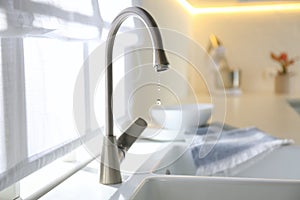 Water drops falling down from tap in kitchen