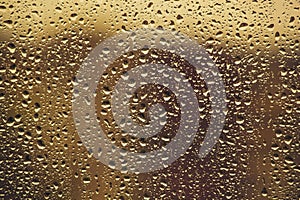 Water drops flow down on the glass in the rain