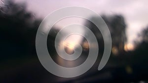 Water drops on front car window in hard stormy rain with blurred background