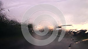 Water drops on front car window in hard stormy rain with blurred background