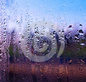 Water drops on the glass of the train on the background of the setting sun railroad