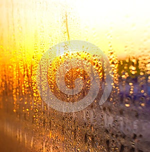 Water drops on the glass of the train on the background of the setting sun railroad