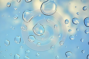 Water drops on glass window over blue sky. Water drops background