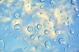 Water drops on glass window over blue sky. Water drops background