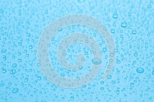 Water drops on light blue background, closeup view