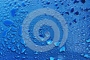 Water drops with light reflection on blue plastic surface as background