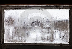 water drops on misted frozen window of rural house