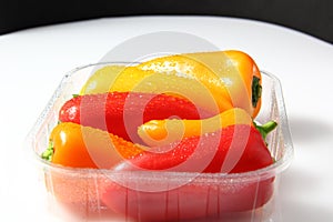 Water drops on peppers of colors with packing of plastic photo