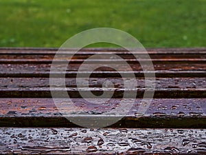 Water drops after rain on a brown wooden bench in a park. Abstract fall or autumn season concept. Selective focus